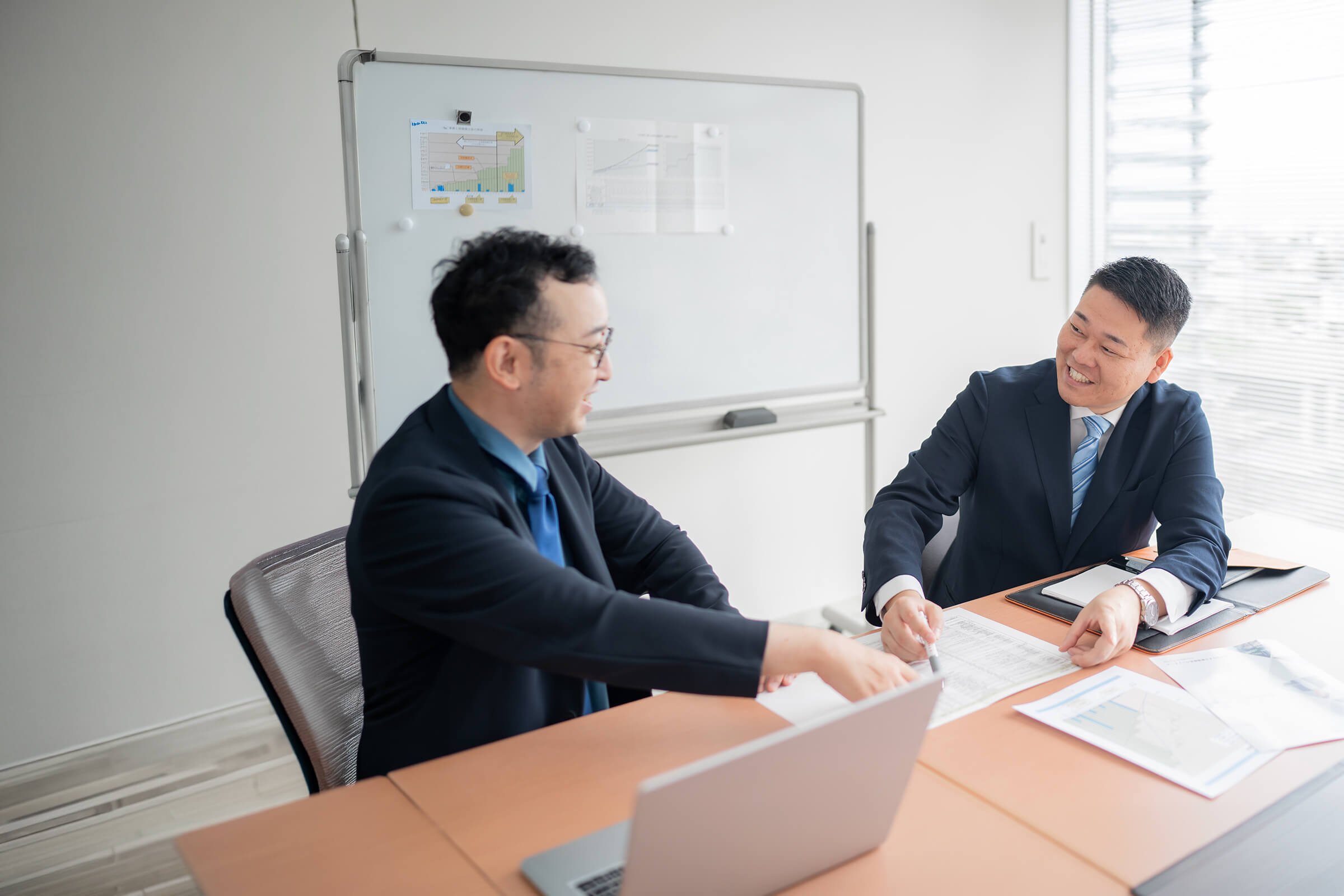 代表と専務がホワイトボードを前に打ち合わせをする様子